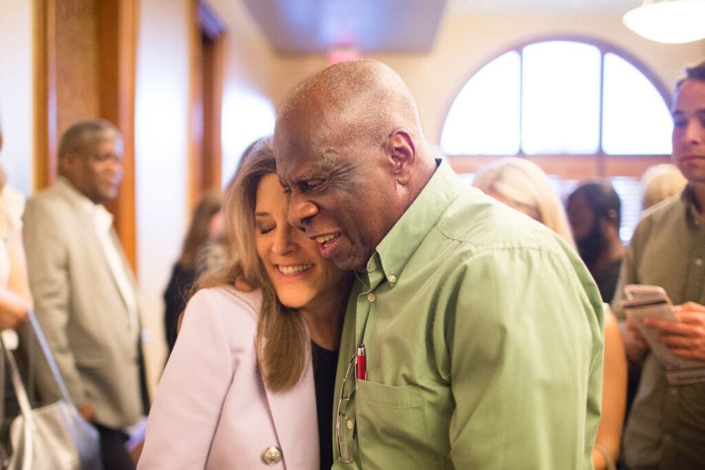 A man and woman hugging in front of a crowd.